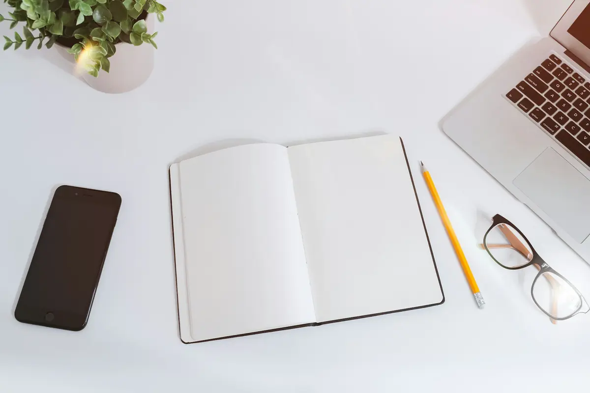 A desk with an open notebook, laptop and phone