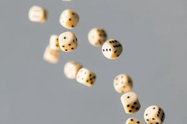 Ivory dice against a grey background representing random selection